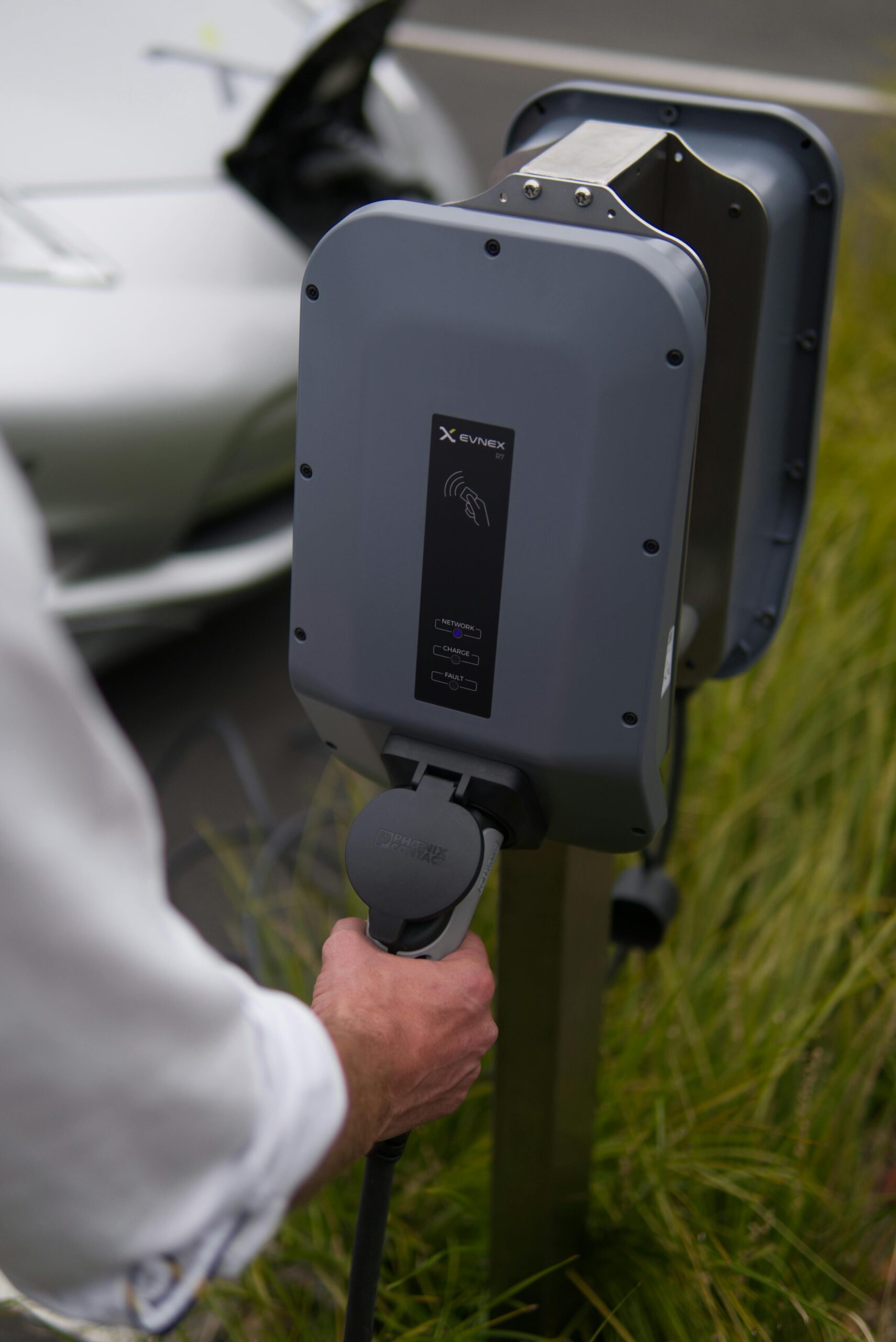 Close-up of a hand connecting an electric vehicle at a charging station in Christchurch, New Zealand.